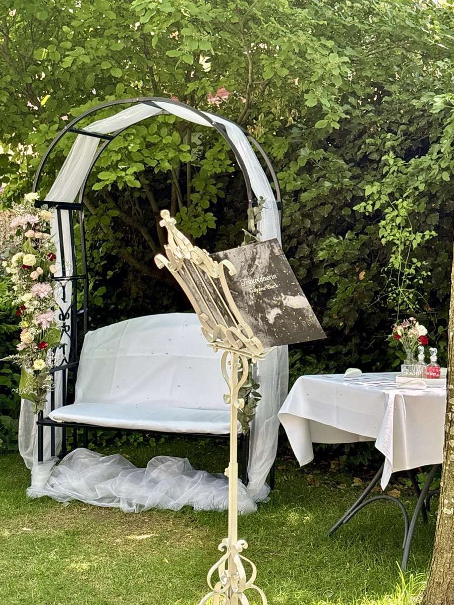 Traubogen mit Blumen, Bank und Rednerpult im Garten - Setting einer freien Trauung